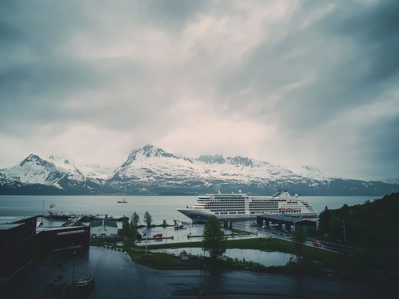 Alaska cruise ship docked near a glacier with snow-capped mountains behind