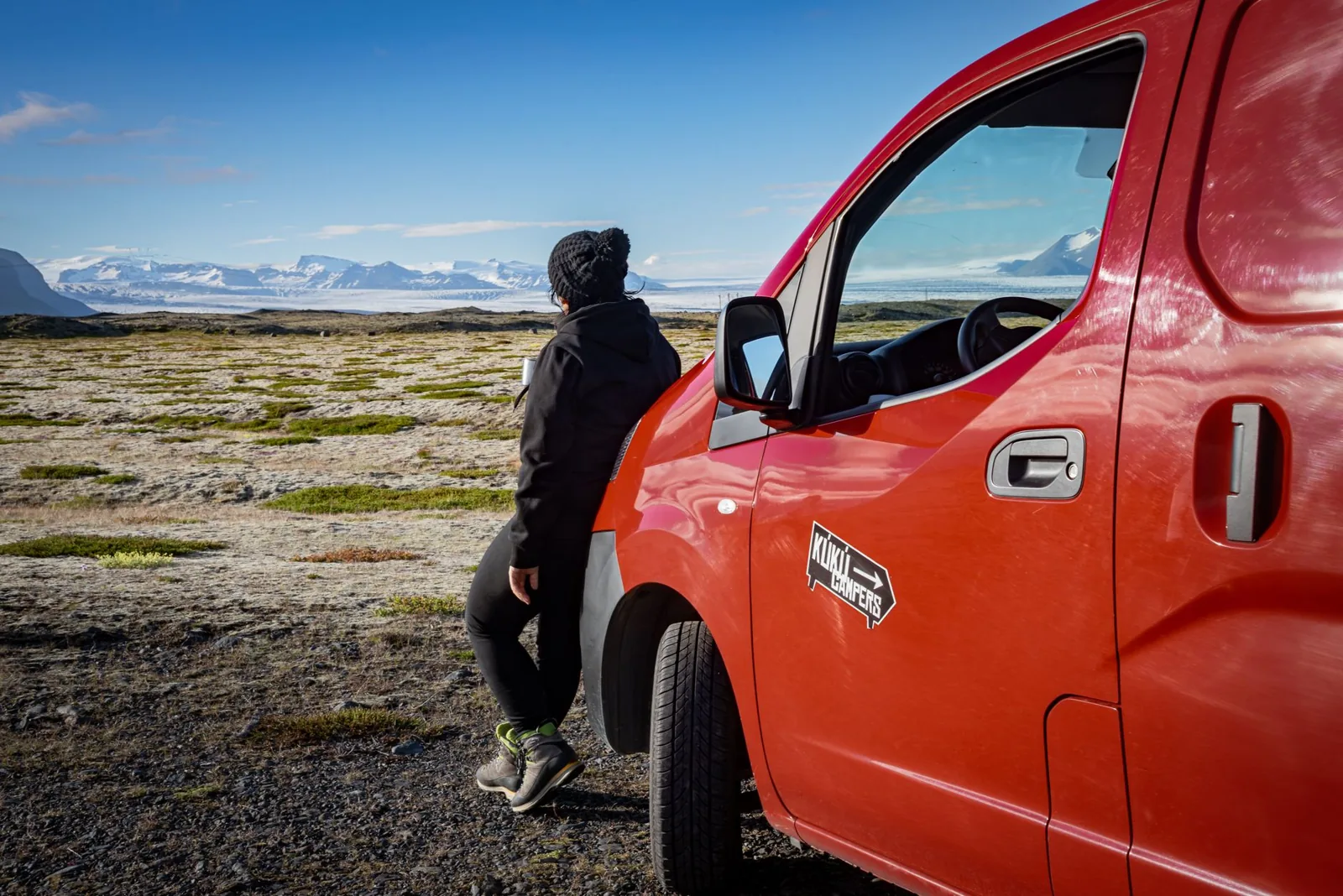 couple cooking beside a rented camper van at a campsite