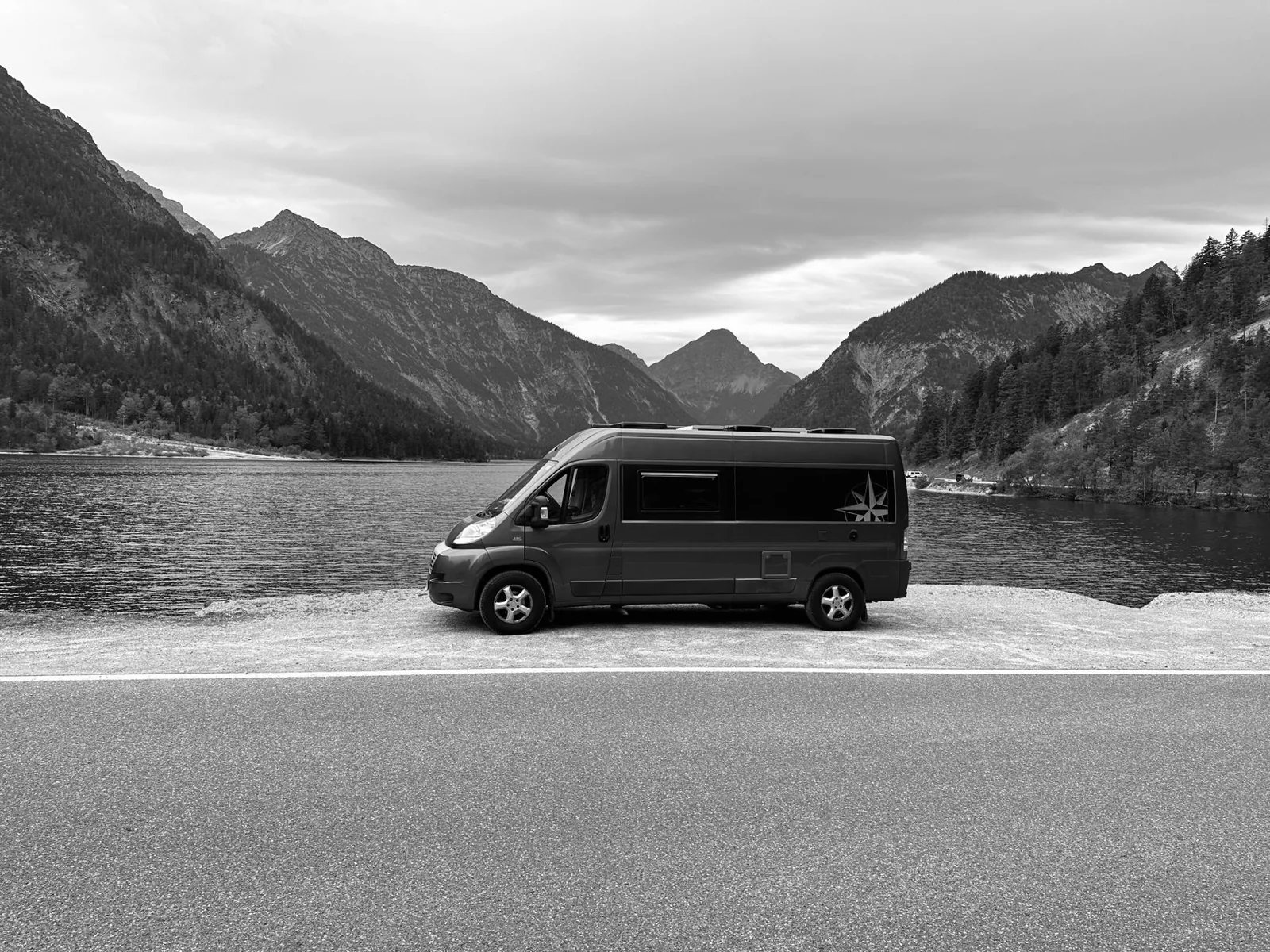A Class B camper van parked at a scenic overlook on a road trip